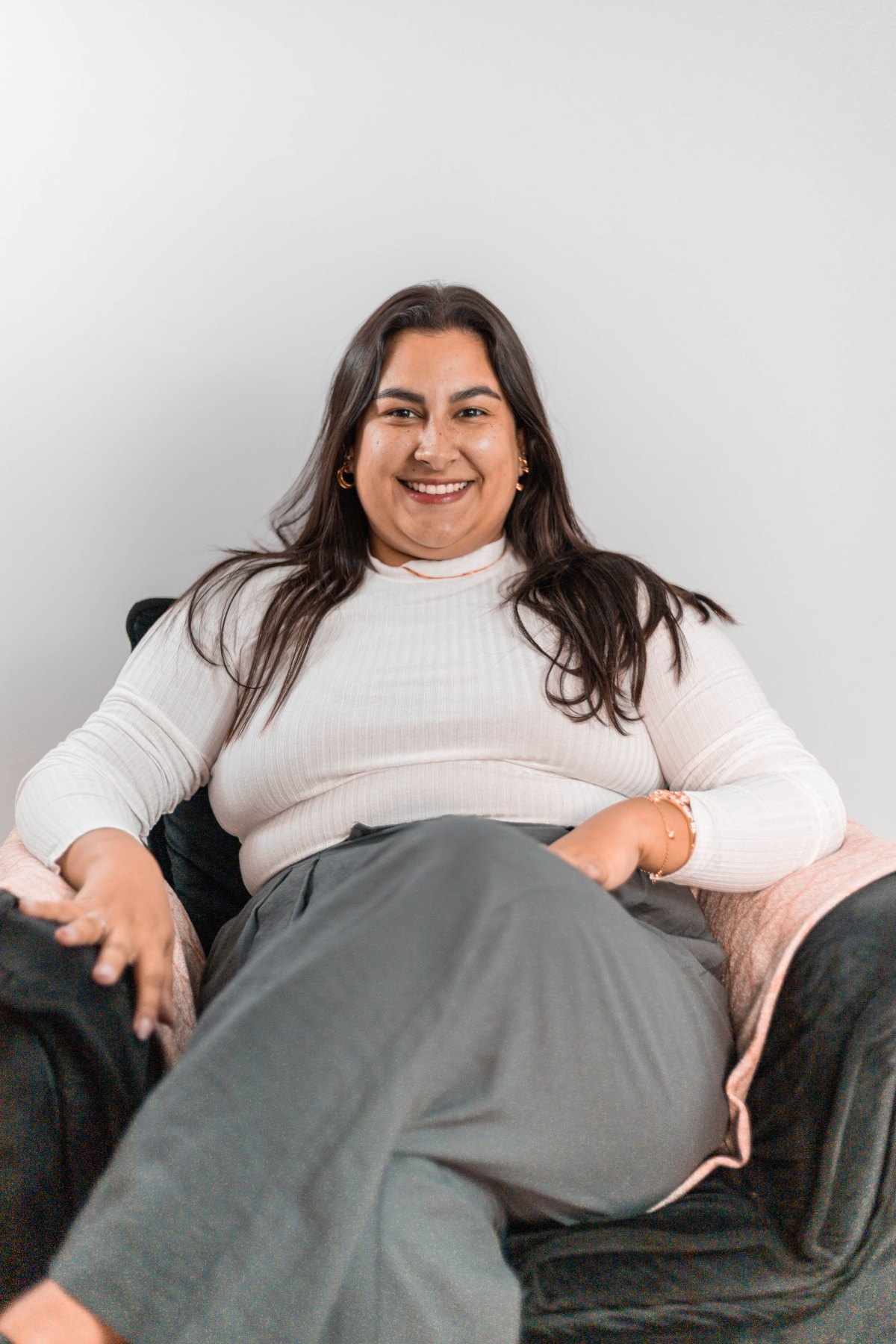 Aline Moitinho sentada em uma poltrona, sorrindo